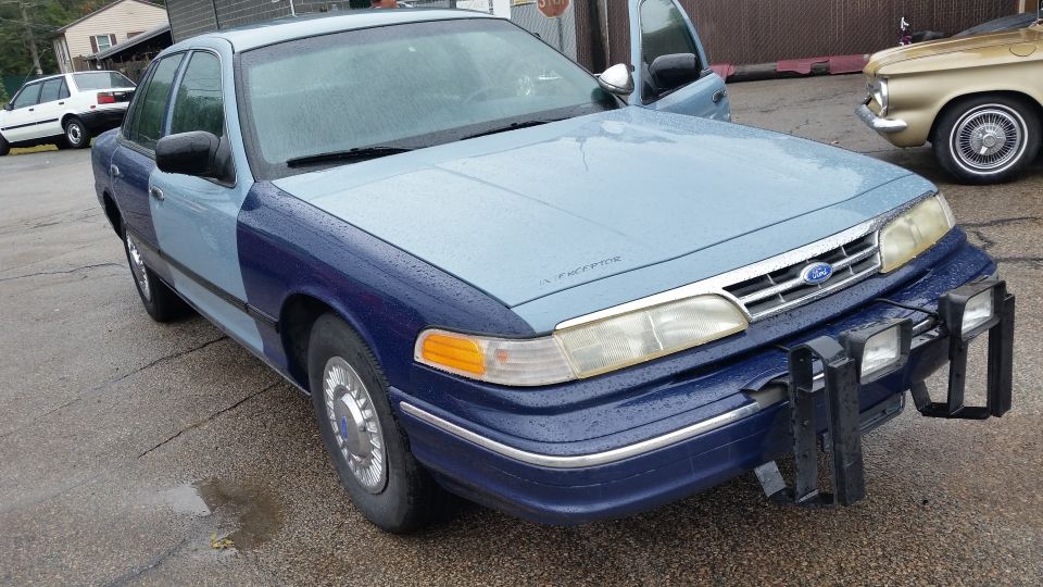 Front three-quarter view of a two-tone blue Ford Crown Victoria with push bar