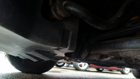 1991 Ford LTD Crown Victoria - Photo of a vehicle's undercarriage with a splash shield and exhaust, not a document.