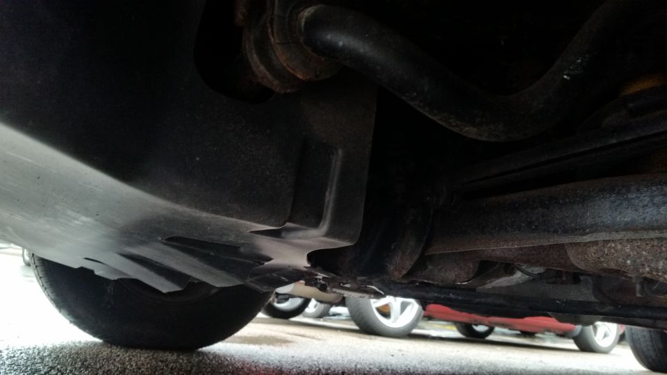 Undercarriage close-up showing plastic shield, exhaust pipe and rusty parts