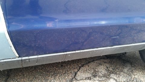 1991 Ford LTD Crown Victoria - Close-up photo of a blue door and rusty rocker panel, not a technical document.