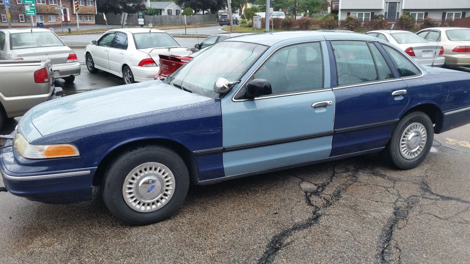 Two-tone blue Ford Crown Victoria sedan parked in a lot