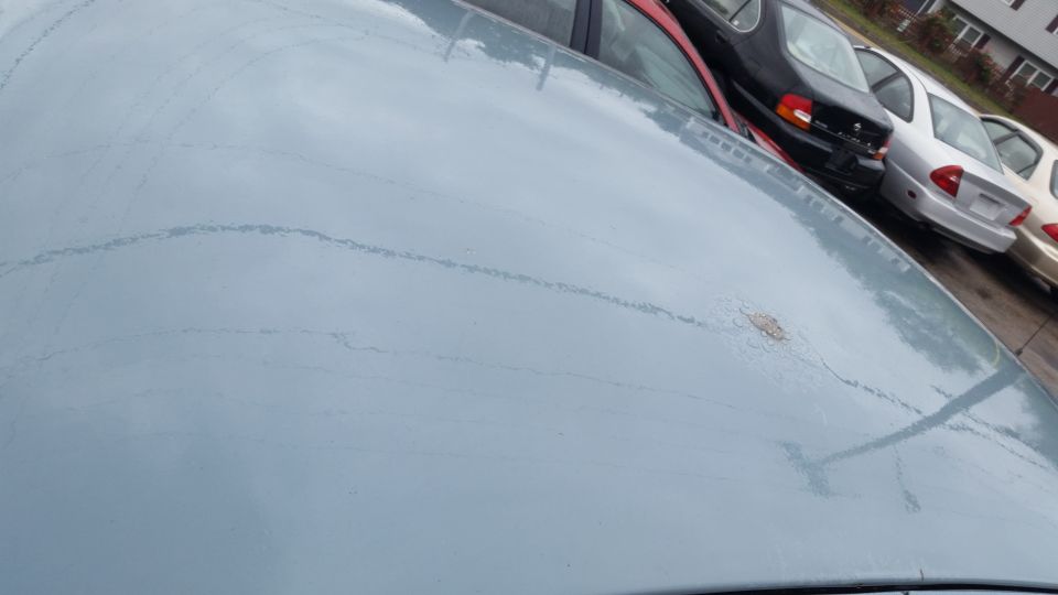 Close-up of a faded blue car roof showing paint cracking