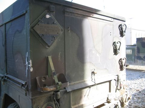 1981 Ford Bronco - A diamond-shaped plaque on a camouflaged military truck humorously states 'MY OTHER TRUCK IS A FULL-SIZE BRONCO'.