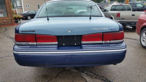1991 Ford LTD Crown Victoria - The rear of a blue Ford Crown Victoria is shown, with other vehicles parked nearby.