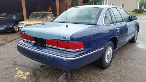 1991 Ford LTD Crown Victoria - A Ford Crown Victoria sedan with a two-tone paint job and visible panel repair is parked outdoors.