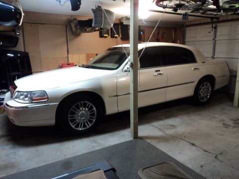 2004 Mercury Grand Marquis - A white sedan is parked inside a garage with various items hanging from the ceiling.