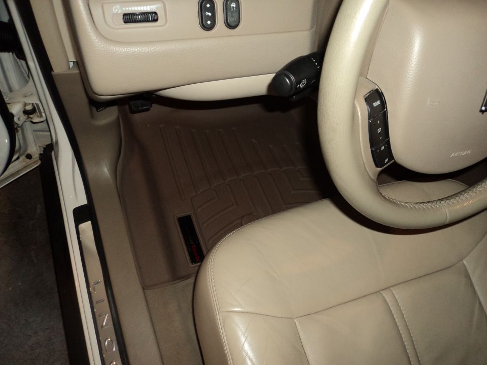 Car interior with beige leather seats, floor mats, and steering wheel. "LINCOLN" is visible on the door sill. "SUPERMOTORS.NET" watermark
