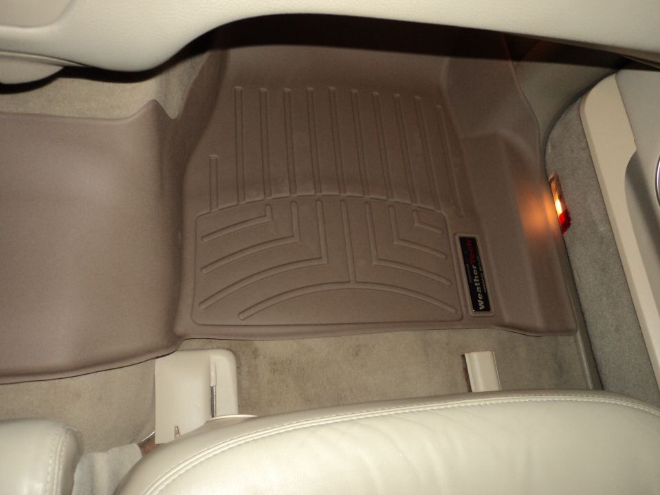 Car interior showing tan WeatherTech floor mats on the driver's side