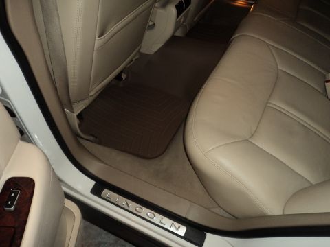 2004 Mercury Grand Marquis - The interior of a car features tan leather seats and dark floor mats, with 'LINCOLN' visible on the door sill.