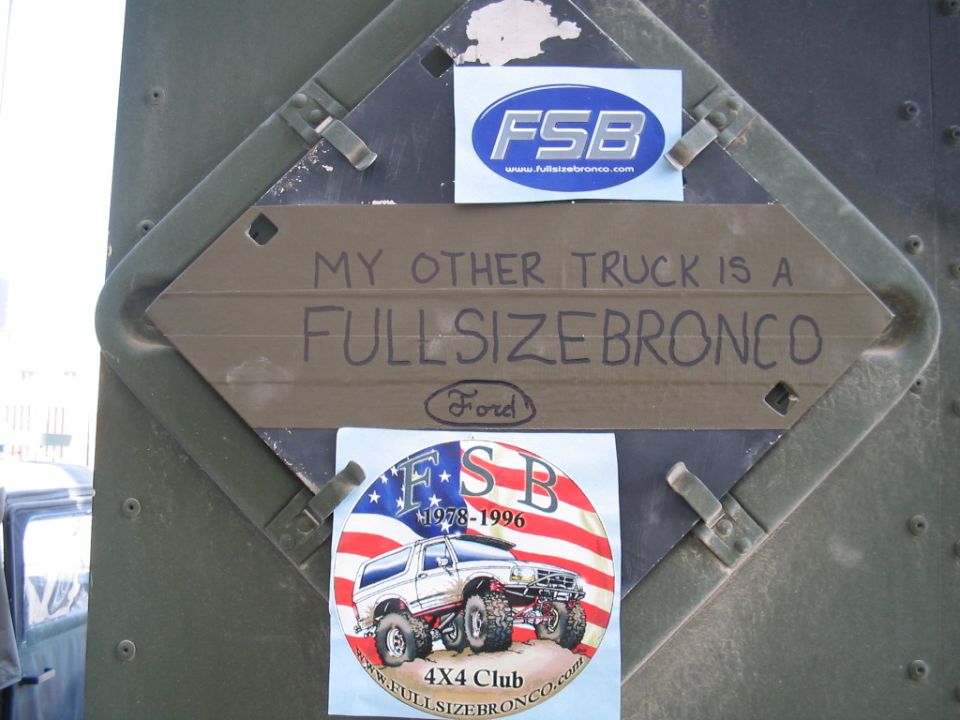 Stickers and a sign that says 'MY OTHER TRUCK IS A FULLSIZEBRONCO' on a green metal surface