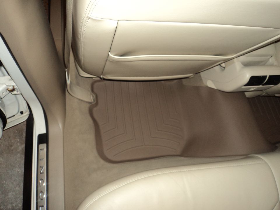 Car interior with beige leather seats and floor mats. "LINCOLN" text is visible on the door sill