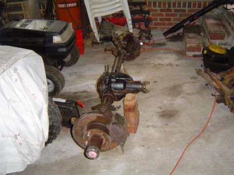 1986 Ford Bronco - Front axle assembly, likely from a truck or SUV, sits on a garage floor.