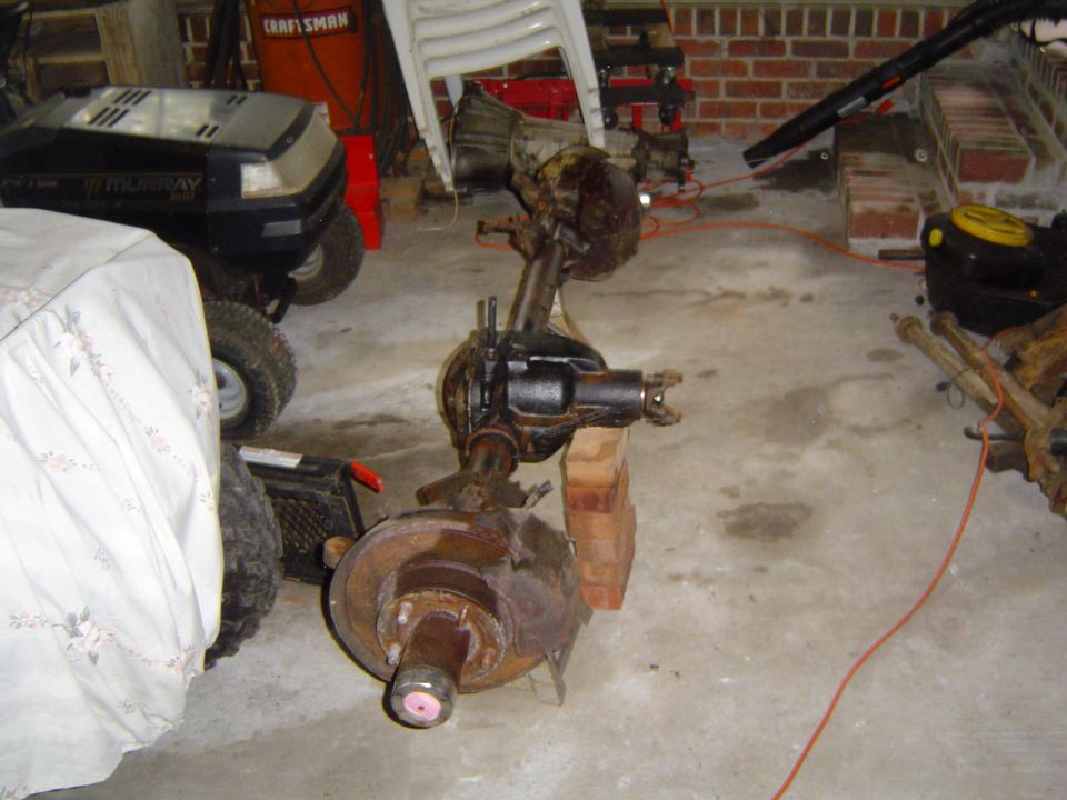 Front axle assembly with disc brake rotor and caliper, supported by wooden blocks