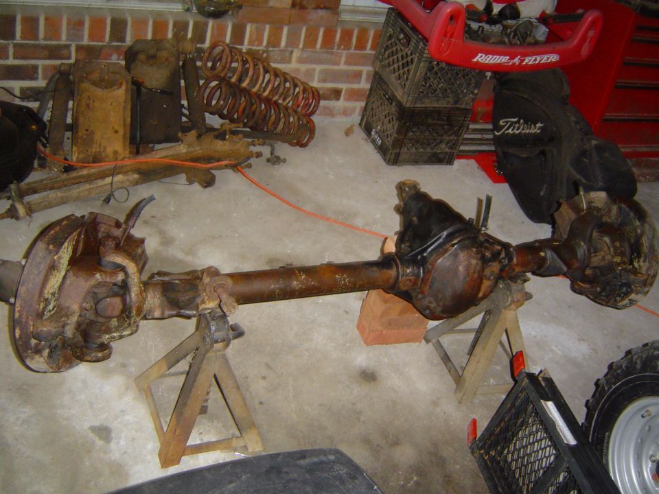 Front axle assembly on jack stands, with springs and shocks in background