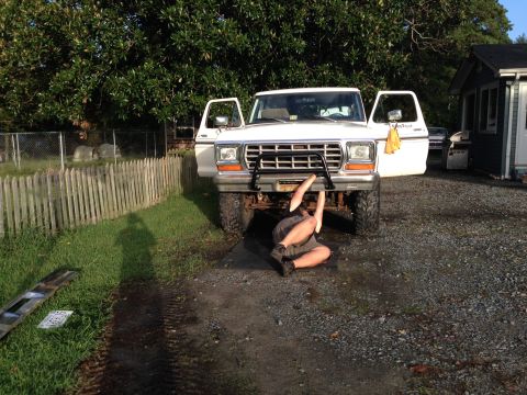 1979 Ford Bronco - A person works on the front of a white 1979 Ford Bronco with its doors open.