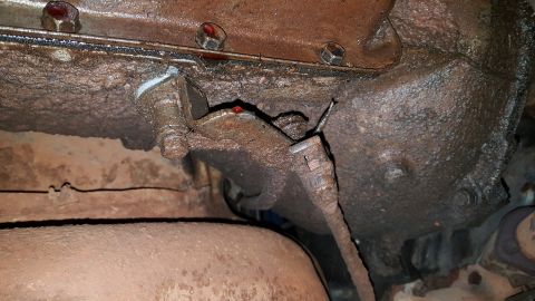 1973 Ford F-100 - Underside view of heavily corroded engine and transmission parts, showing signs of oil leakage and wear.