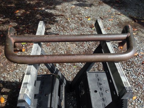 1979 Ford Bronco - A weathered bull bar rests on sawhorses outdoors, showing signs of rust and age.