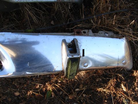 1973 Ford Ranchero - Chrome bumper part lying on the ground amidst dry grass and debris.