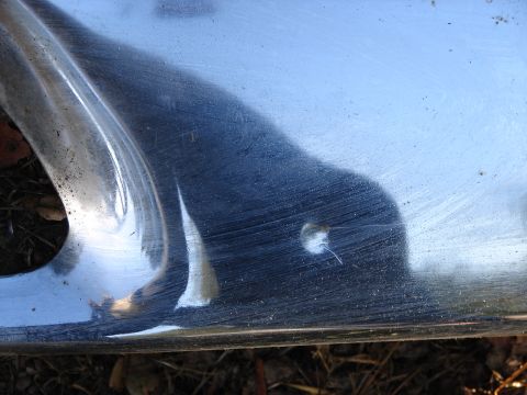 1973 Ford Ranchero - Close-up of a chrome bumper with a small hole and visible scratches.