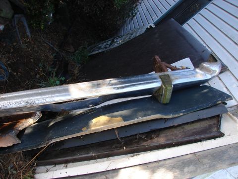 1973 Ford Ranchero - Stacked car parts including a chrome bumper and body panels.
