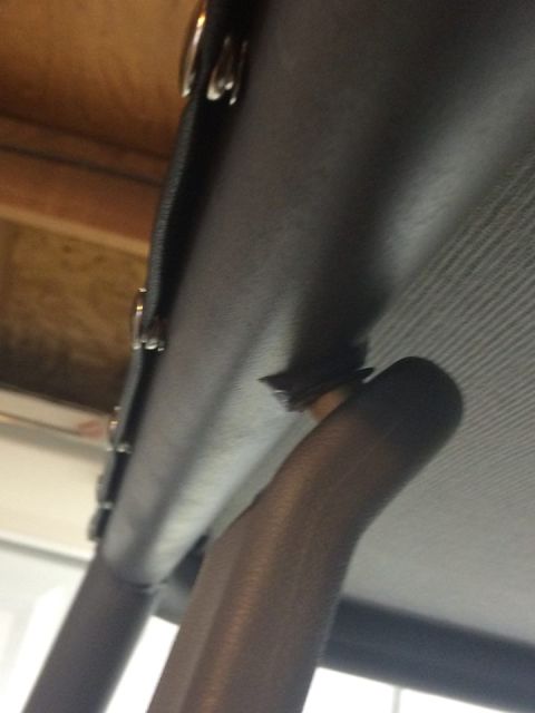 1995 Ford Bronco - A close-up view of the interior roll cage shows a torn section near where a finger is pointing.
