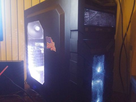 2000 Mercury Grand Marquis - A black computer tower with a clear side panel, illuminated by internal lights, features an American flag sticker on its front.