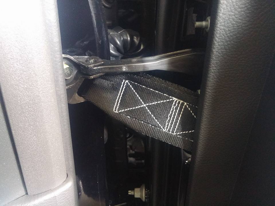 Close-up of a black seatbelt strap and metal anchor point inside a vehicle