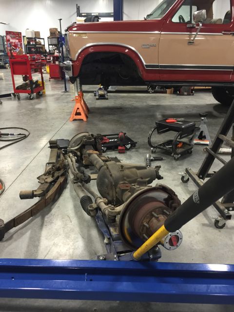 1984 Ford Bronco - The front axle assembly of a Ford Bronco is being worked on in a garage, garage setting.
