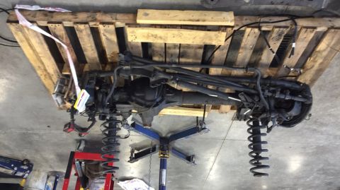 1984 Ford Bronco - Front axle and suspension components are shown disassembled and mounted on a pallet.