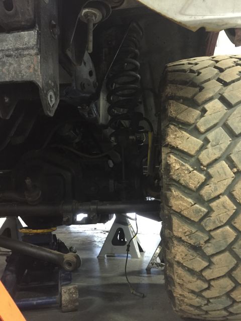 1984 Ford Bronco - Close-up view of a vehicle's undercarriage and tire, supported by jack stands.