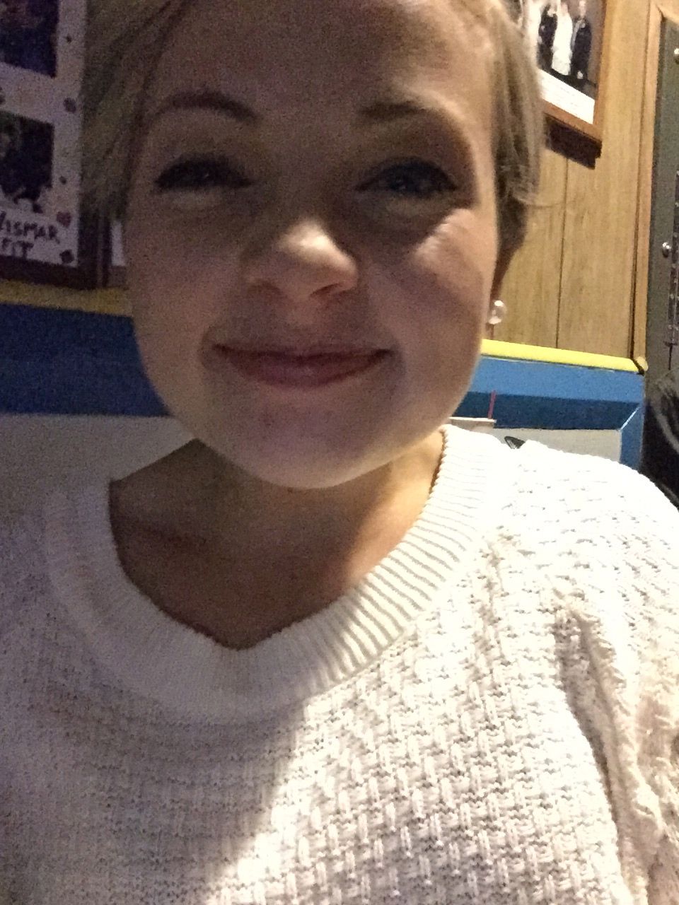 Woman's face looking at the camera, wearing a white sweater