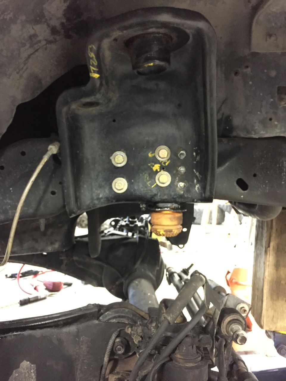 close-up of vehicle suspension part with yellow markings and bolts