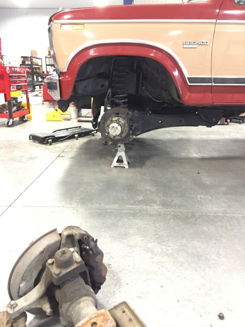 1984 Ford Bronco - The front axle and suspension components of a 1984 Ford Bronco are disassembled for repair in a workshop.