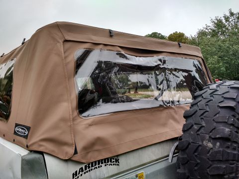 1992 Ford Bronco - tan replacement soft top on a Ford Bronco with clouded plastic windows, spare tire and Hardrock Off Road Park decal.