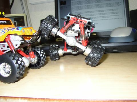 1989 Ford Bronco - Close-up of a toy monster truck's suspension and wheels, with another toy truck partially visible.