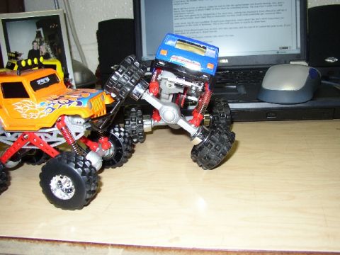 1989 Ford Bronco - Toy monster trucks are positioned on a desk, with a laptop and mouse in the background.