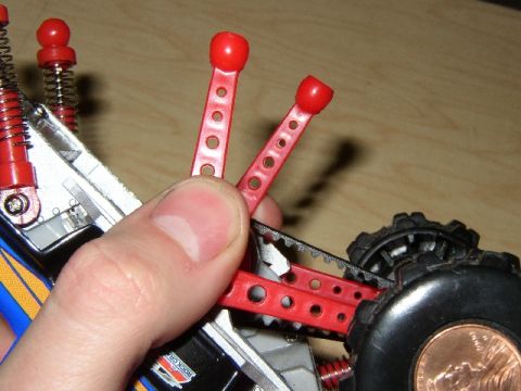 1989 Ford Bronco - A close-up shows a red plastic component of a toy car, with a finger and thumb manipulating it near a tire.