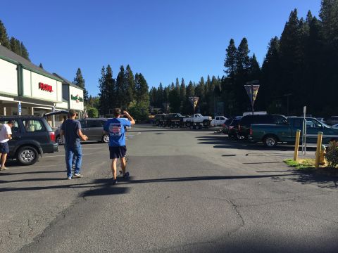 1989 Ford Bronco - A sunny day in a parking lot with several vehicles and people walking around, set against a backdrop of trees.