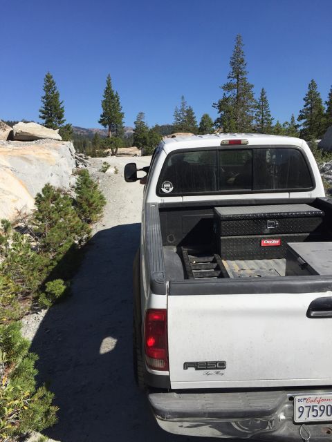 1989 Ford Bronco - A white F250 Super Duty pickup truck is parked on a dirt road with a toolbox in the bed.