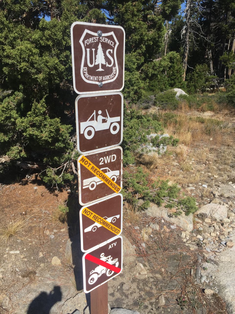 Forest Service signs on a post, showing icons for a jeep, 2WD vehicle, and ATV