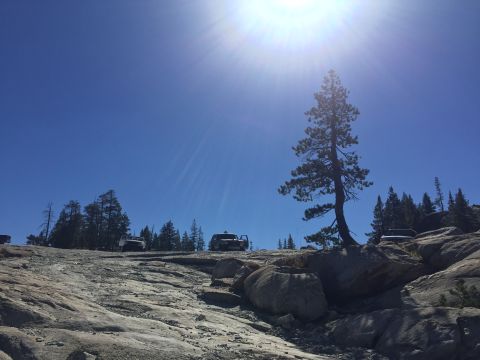 1989 Ford Bronco - Multiple SUVs are parked on a , rocky landscape with a clear blue sky overhead.