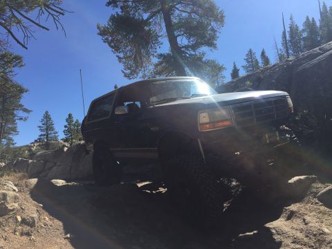 1989 Ford Bronco - This 1989 Ford Bronco is shown off-roading on a , rocky path under a clear blue sky.