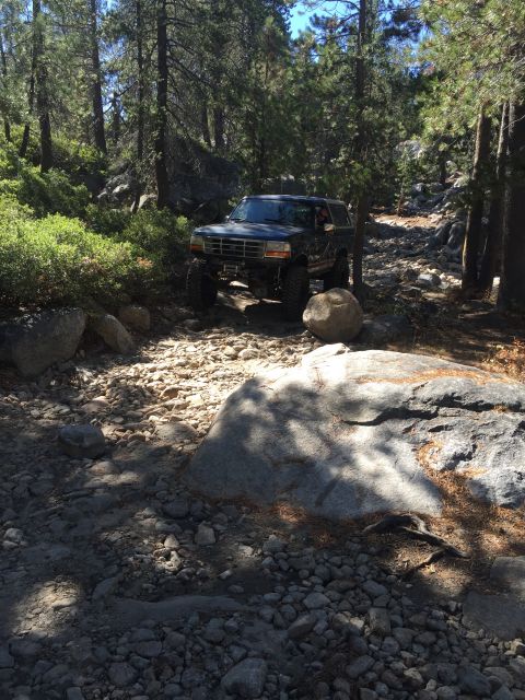 1989 Ford Bronco - This 1989 Ford Bronco is shown tackling a challenging rocky trail in a wooded area.
