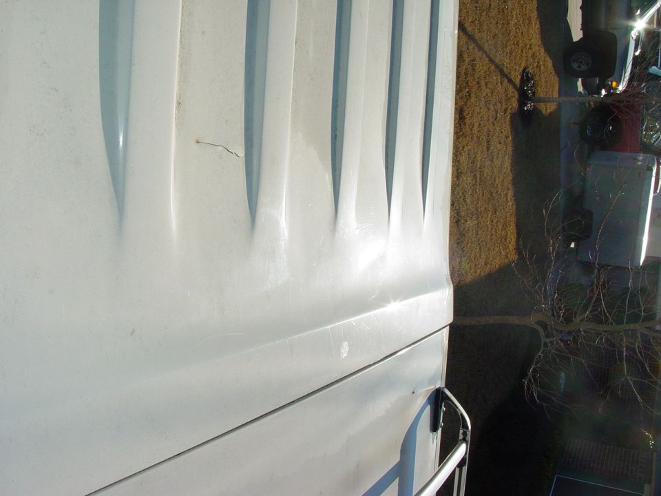 Sideways close-up of a white vehicle body panel with a fender flare