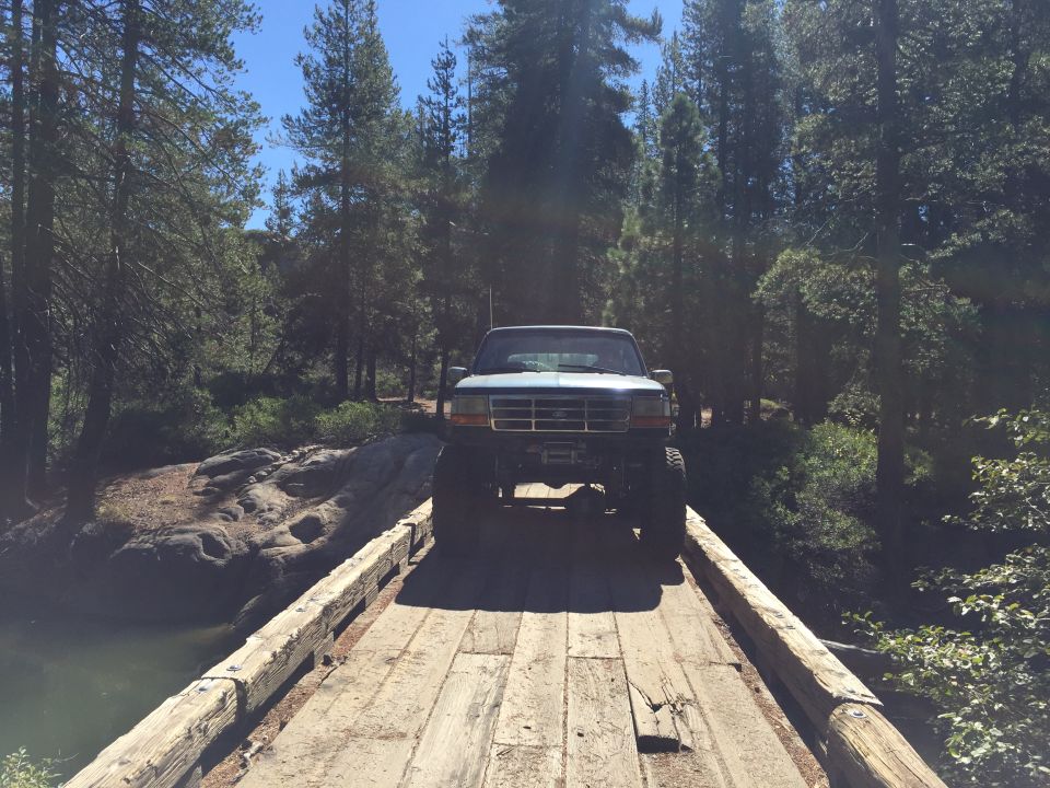 Lifted pickup truck with winch on a wooden bridge in a forest
