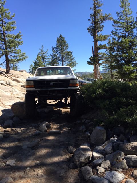 1989 Ford Bronco - This lifted 1992 Ford F-150 navigates a challenging rocky terrain under a clear blue sky.