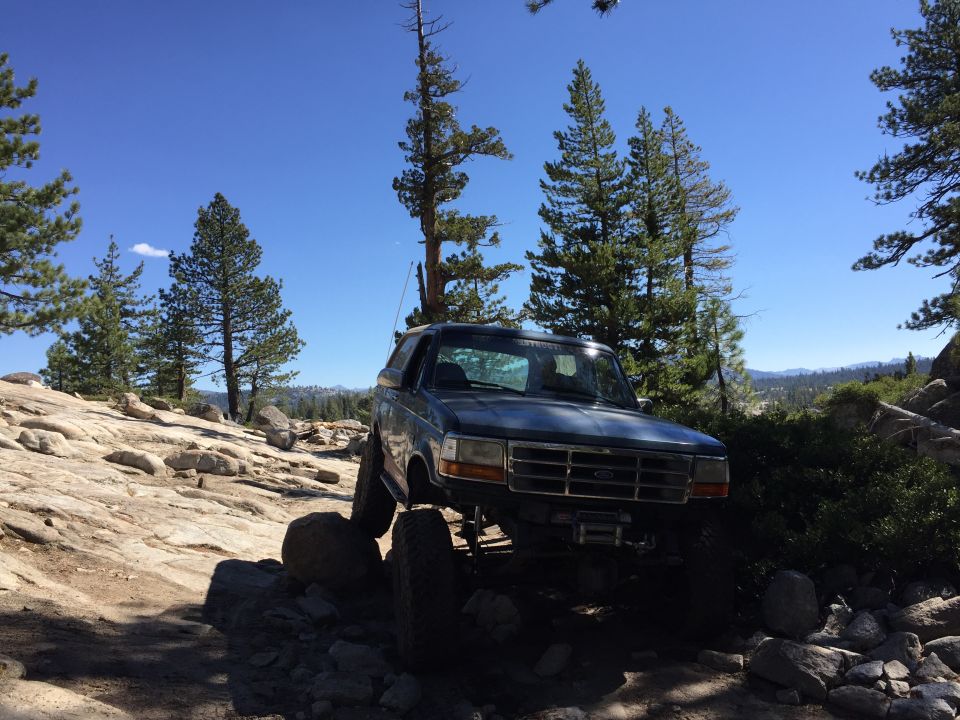 Dark blue SUV with a winch on the front bumper, driving over rocks on a dirt trail