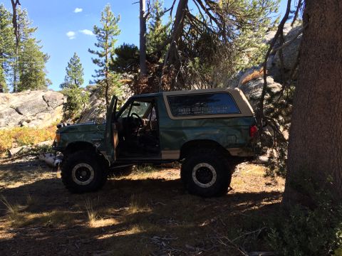 1989 Ford Bronco - Off-road 1989 Ford Bronco parked in a wooded area with rocky terrain.
