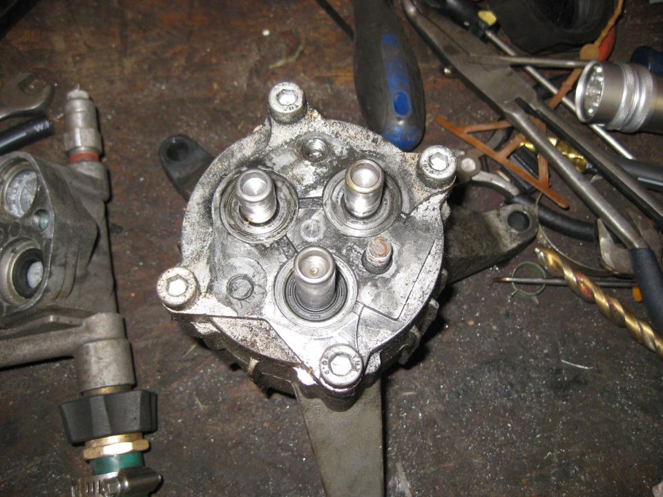 Close-up of a pressure washer pump with tools scattered around