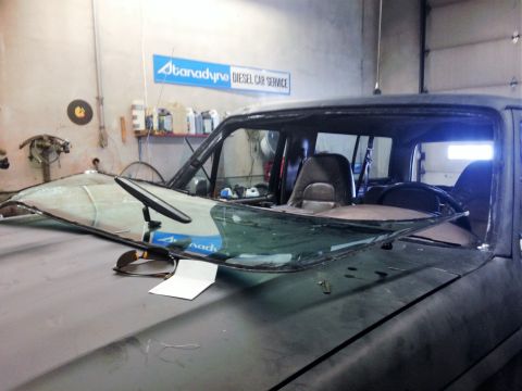1992 Ford Bronco - A 1992 Ford Bronco is shown with a severely damaged windshield, likely in a repair shop.